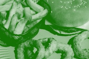 Basket of fries, cheeseburger, onion rings on a table.