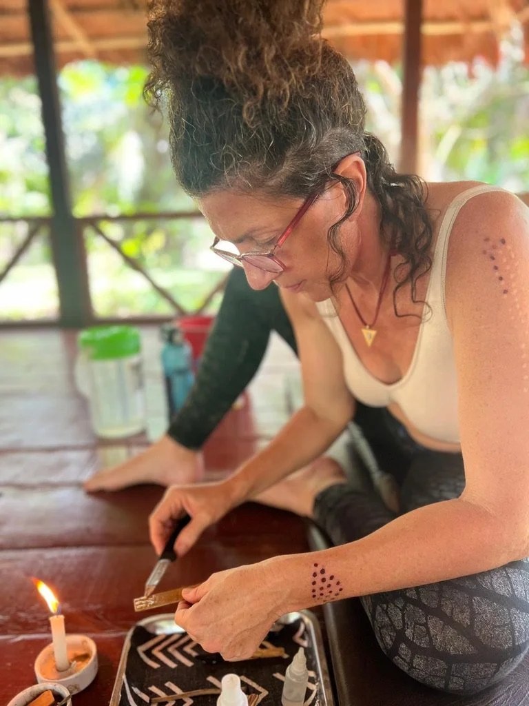 Practitioner preparing Kambo medicine on a tray with a candle, knife and bottles